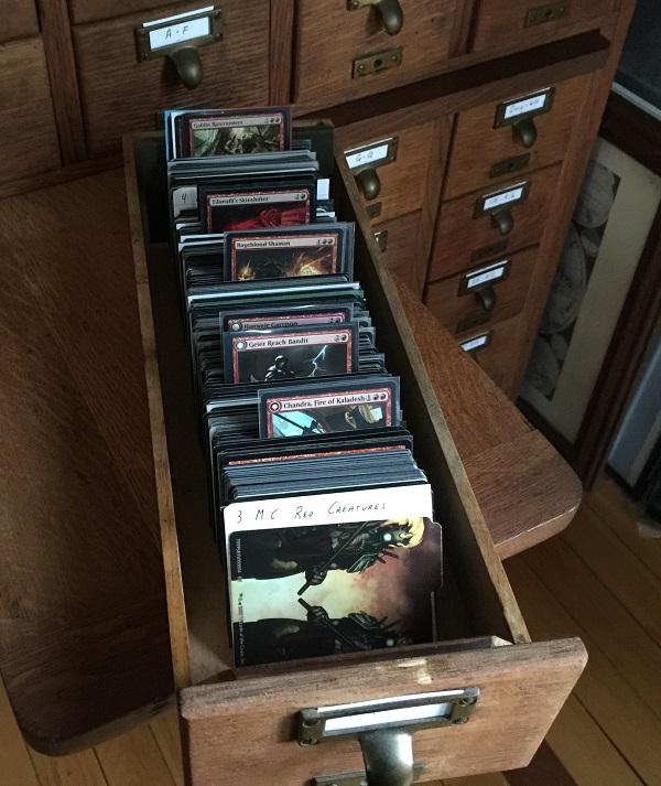 A drawer of the card catalog sits on a table, filled with organized Magic cards.